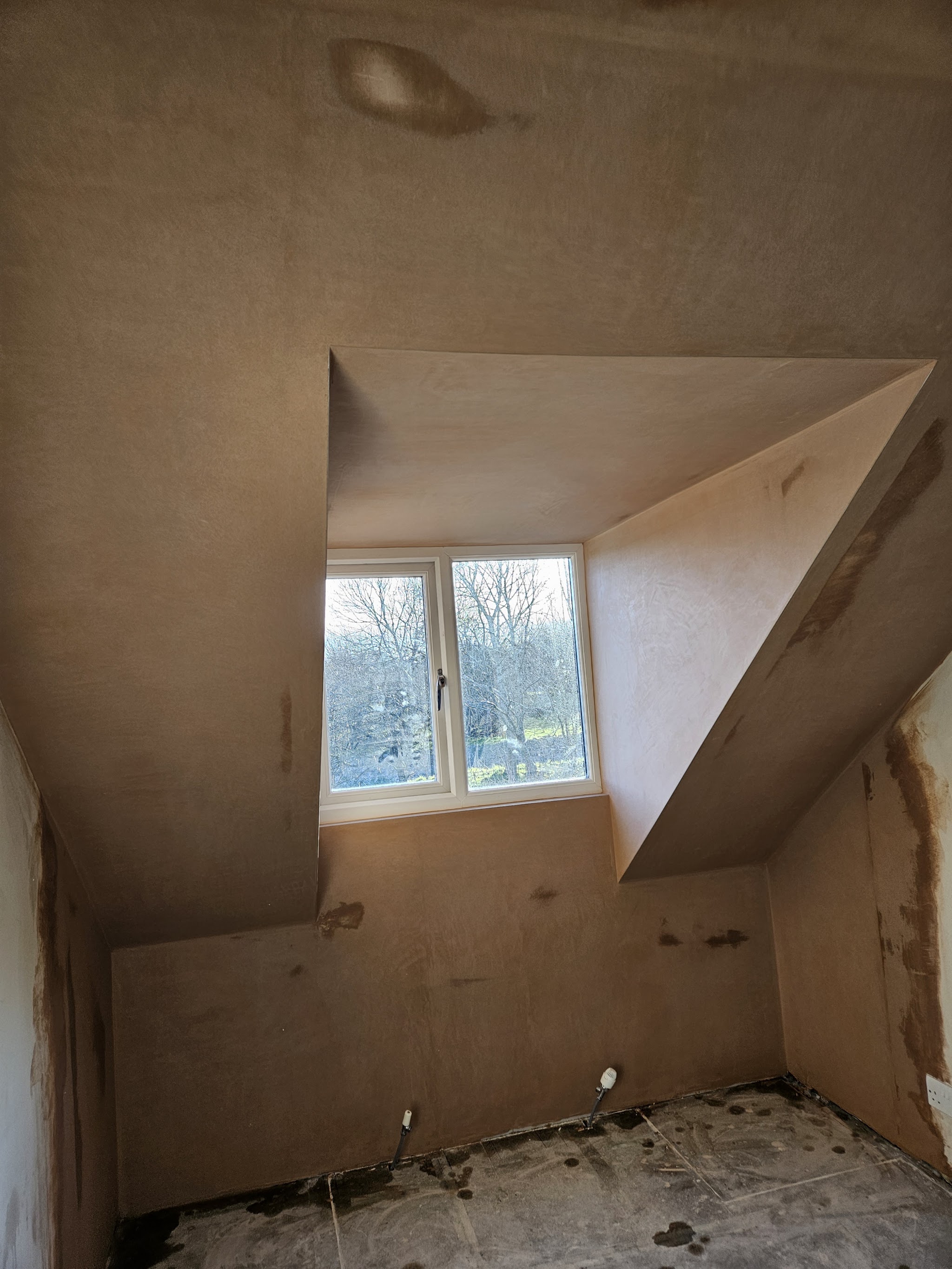 A dormer room with fresh plaster on the walls