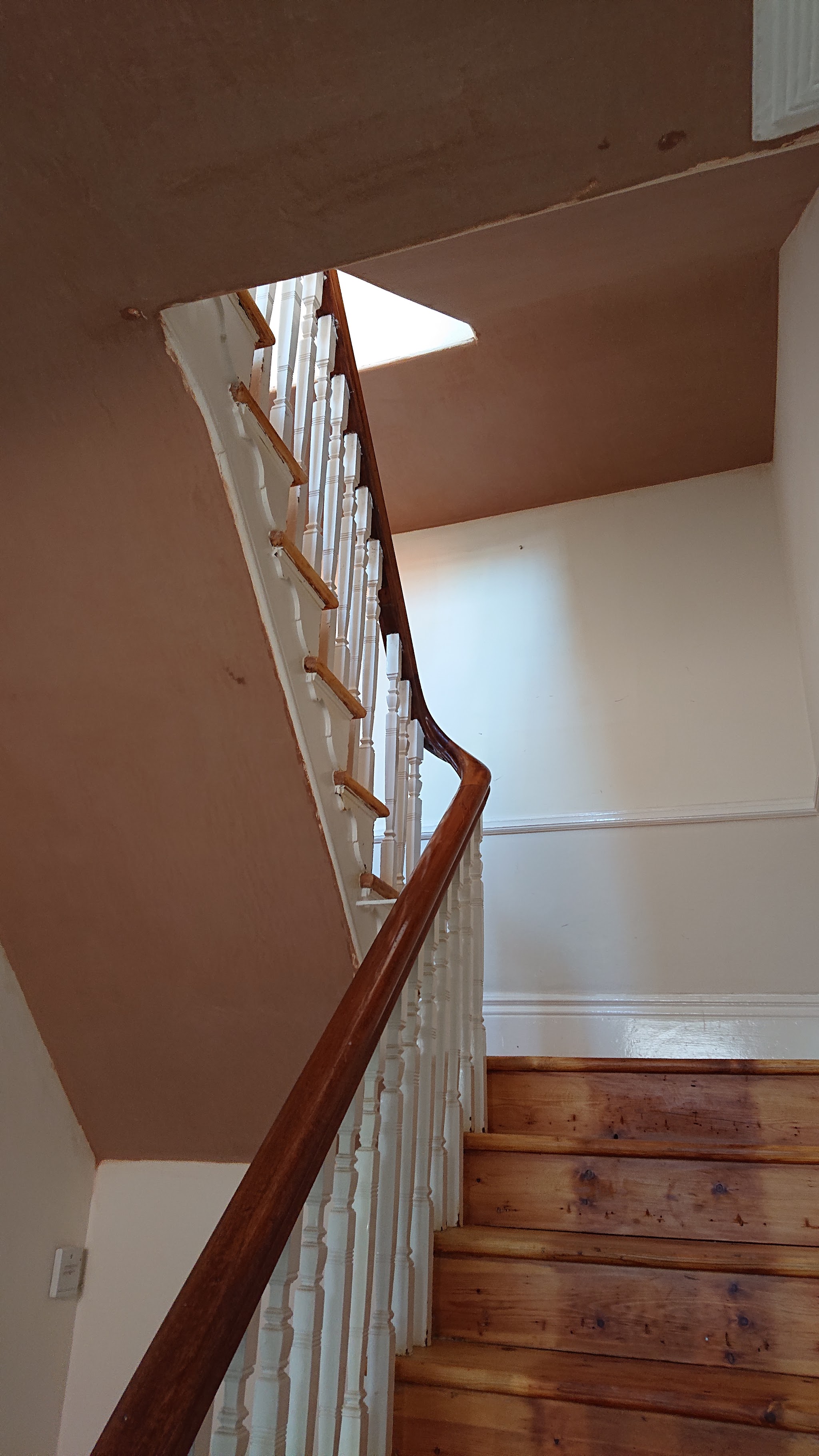 A staircase with freshly plastered walls and a wooden banister