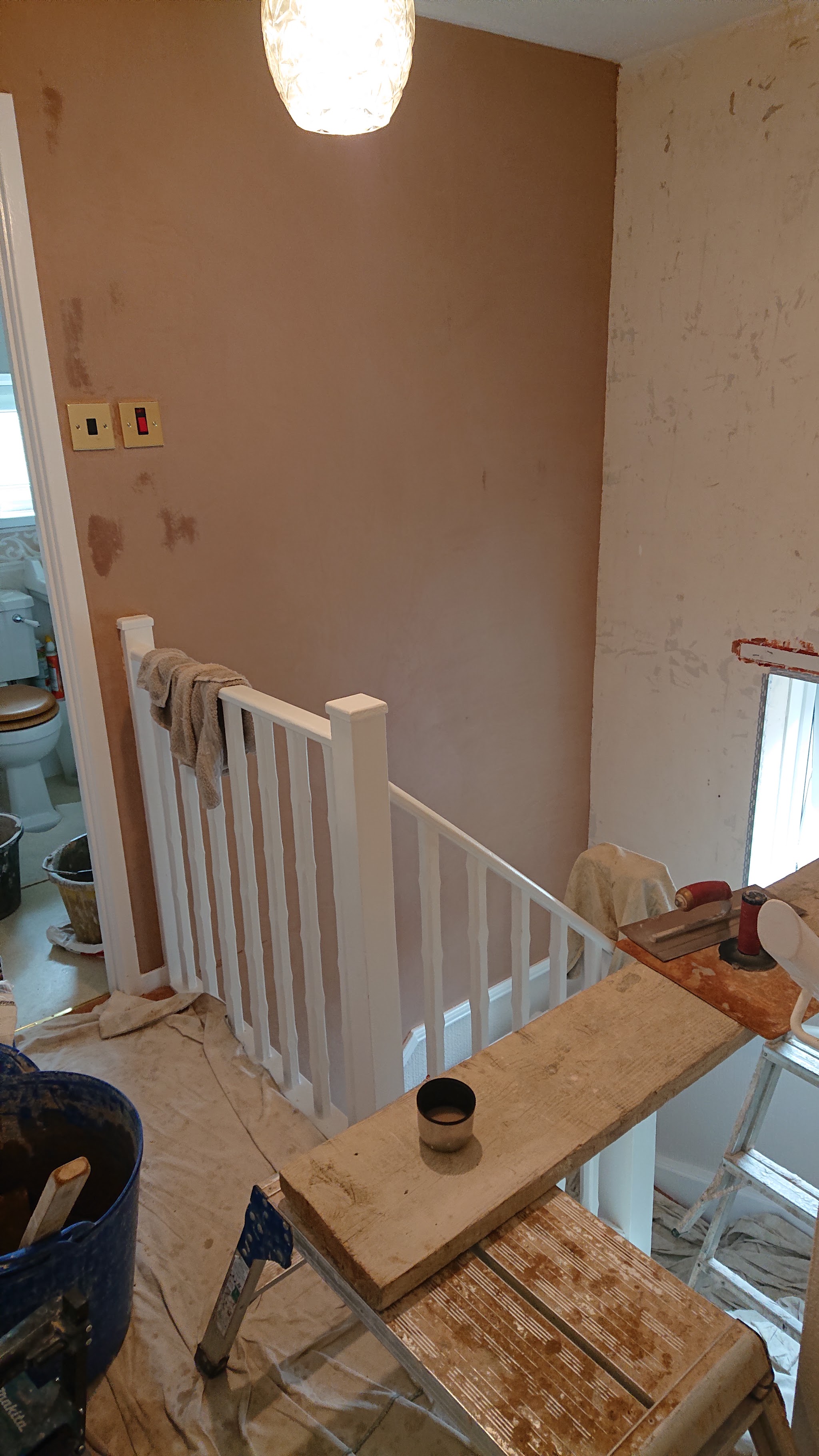 A stairwell with fresh plaster and a wooden banister