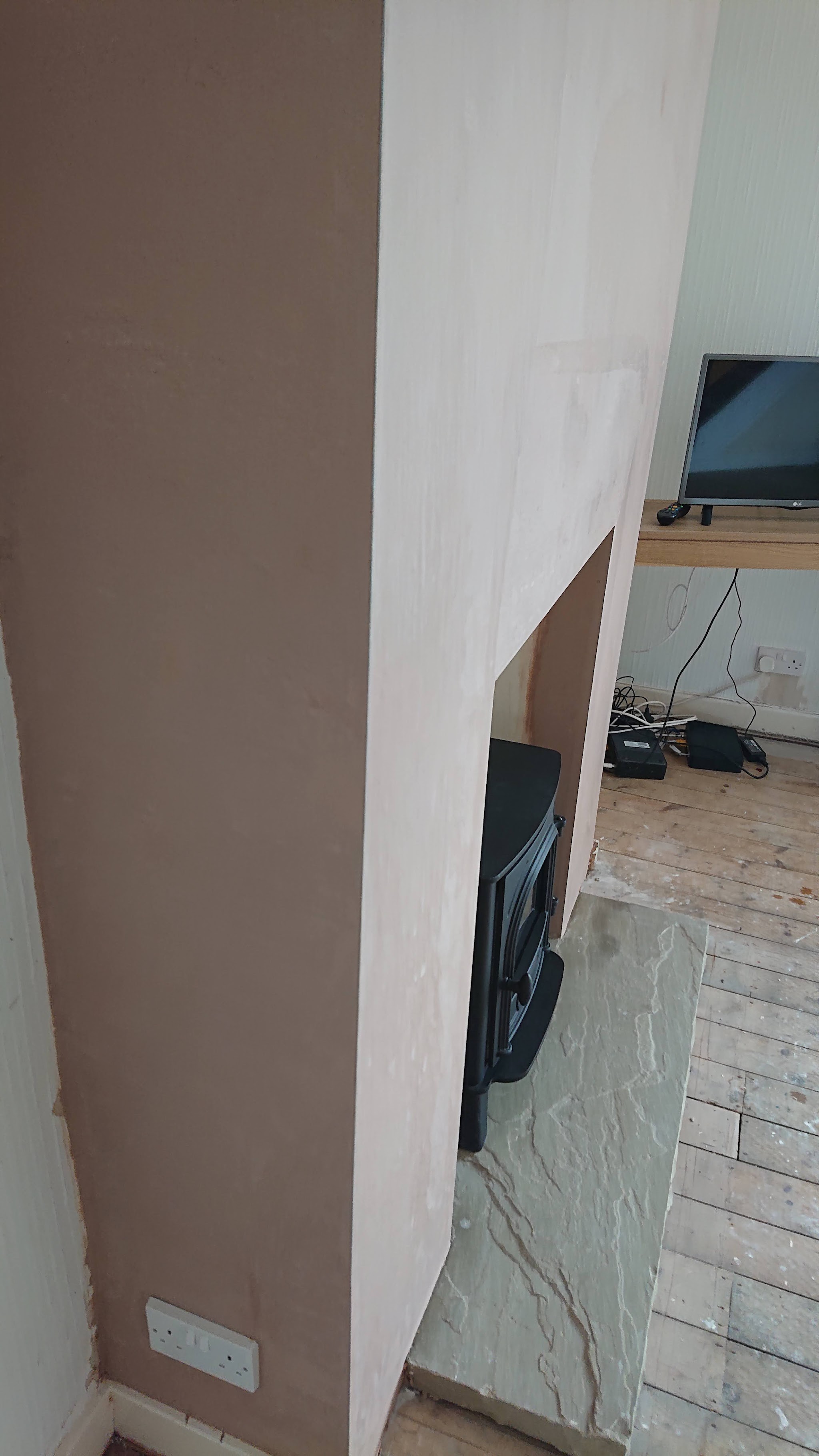 A smooth plastered chimney breast beside a stove