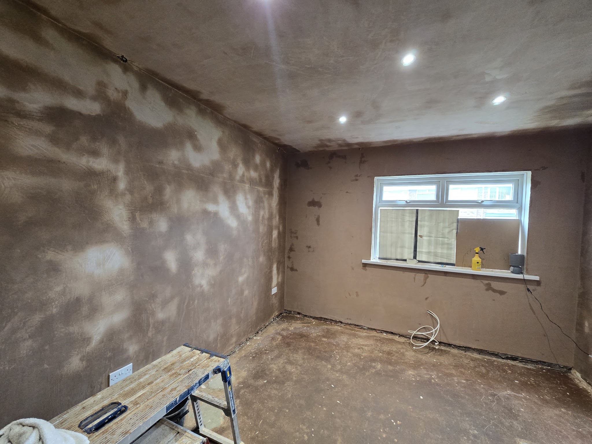 A bay-window room with a freshly plastered ceiling and beam